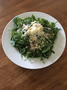 Salad made from spinach, arugula, raw aged cheddar grass-fed cheese, Brazil nuts, sauerkraut, and lacto-fermented ginger carrots.